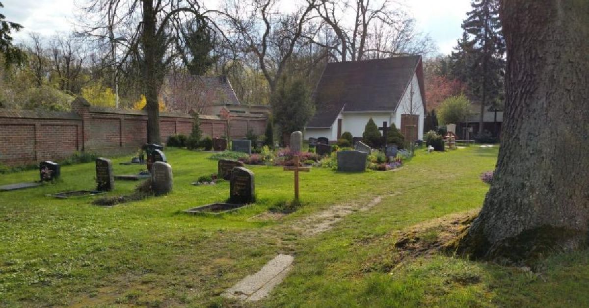 Kleine Kapelle auf einem Friedhof mit Grabsteinen.