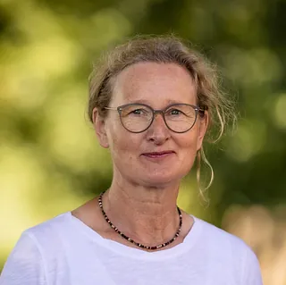 Porträt einer lächelnden Frau mit kurzen weißen Haaren.