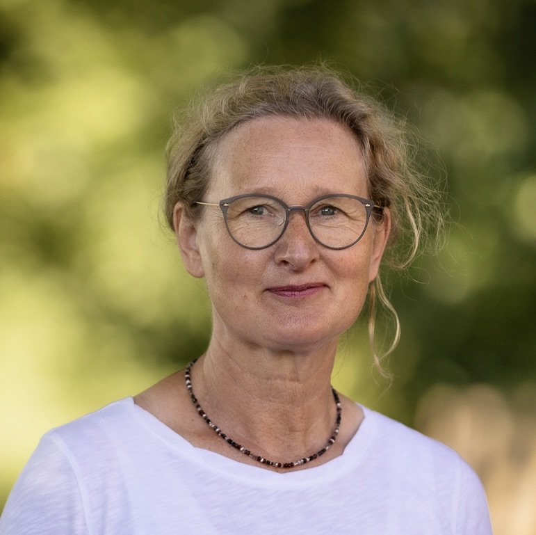 Porträt einer lächelnden Frau mit kurzen weißen Haaren.
