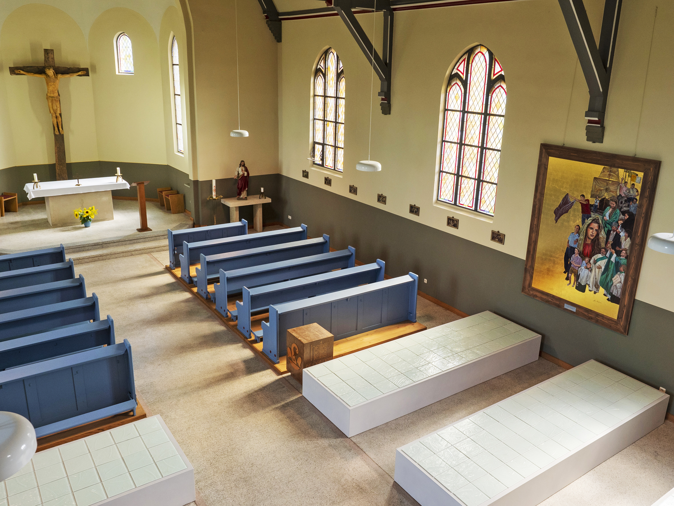 Kircheninnenraum mit Bänken, Altar, Kruzifix und einem großen Gemälde.