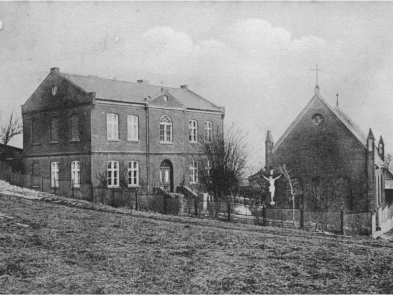 Historisches Foto einer Backsteinkirche und eines Pfarrhauses mit Kruzifix.