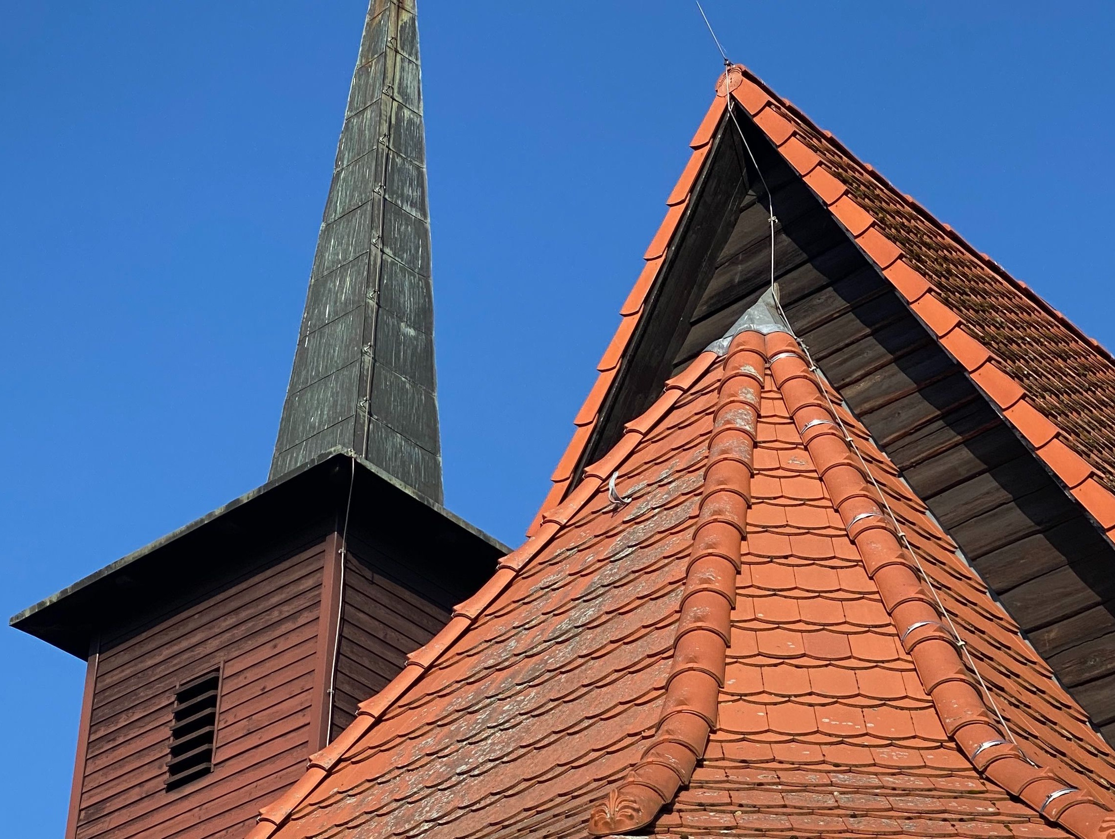 Nahaufnahme des roten Ziegeldachs und des hölzernen Turms.