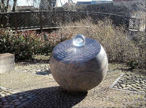 Steinernes Denkmal mit gläserner Kugel und Inschrift.