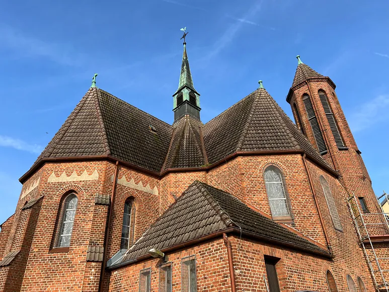 Äußeres einer Backsteinkirche mit mehreren Türmen.