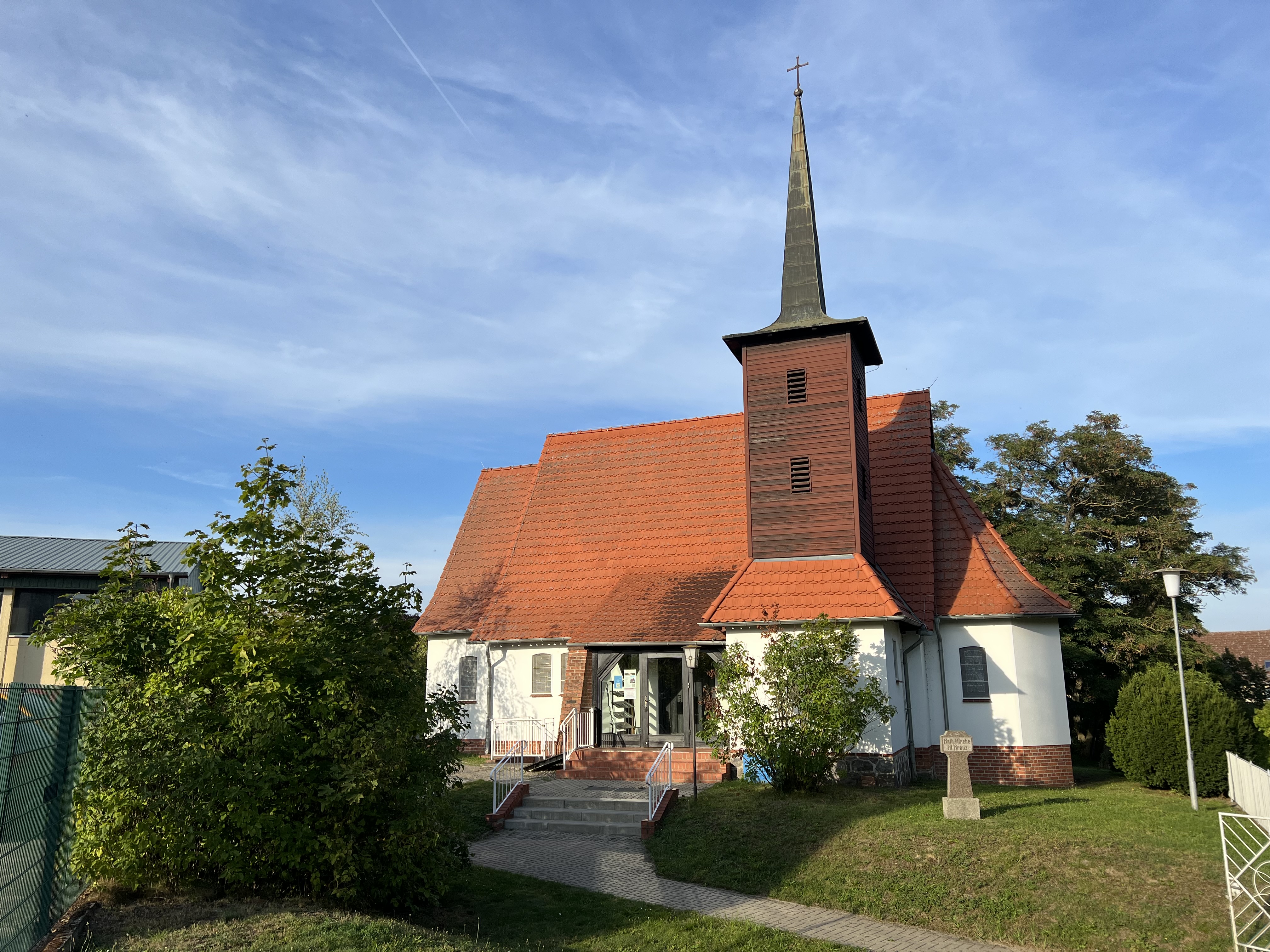 Weiße Kirche mit rotem Ziegeldach und hölzernem Turm.