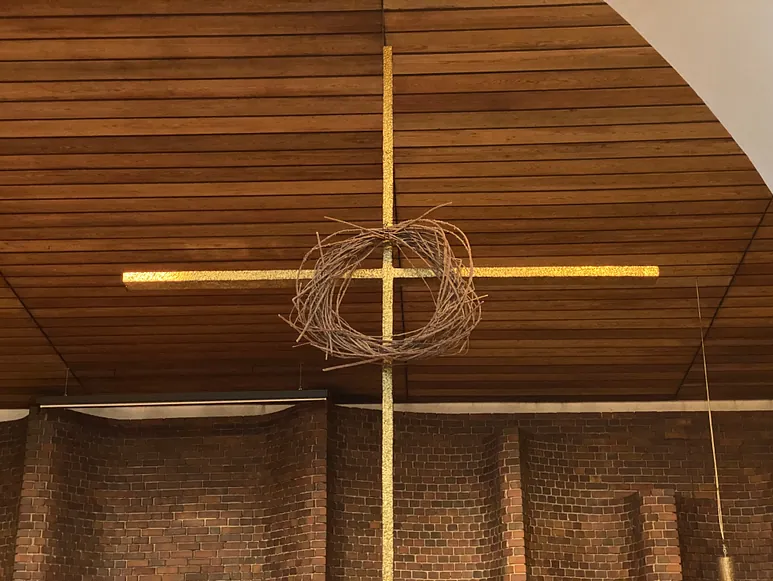 Ein Kreuz mit einem Dornenkranz hängt von der Decke.
