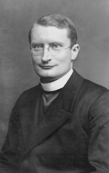 Sepia-Porträt eines Mannes mit Brille und Priesterkragen.